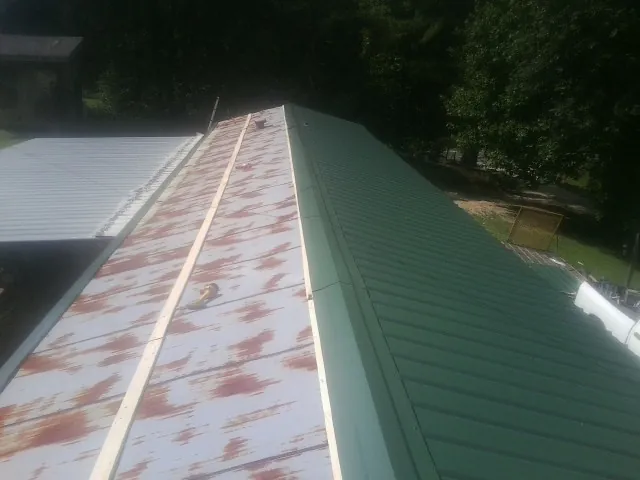 Old rusted panels beside newly installed green metal roofing — Wind Damage Roof Repair by Roofing Brothers in Woonsocket