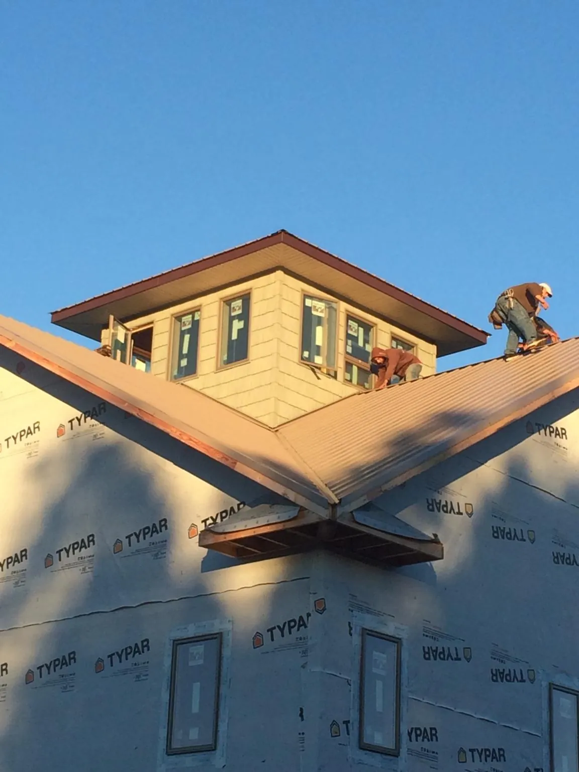 Roofers working around a rooftop cupola on a new metal roof at sunset — Roof Waterproofing in Woonsocket by Roofing Brothers